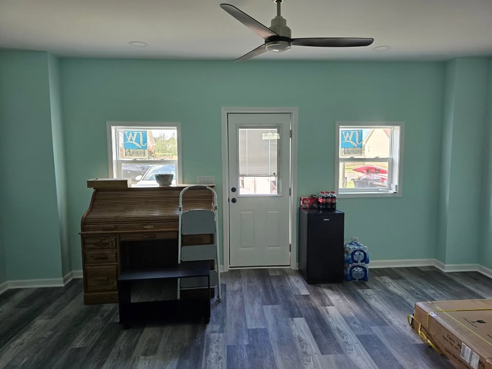 Living space with dark plank flooring, light green walls, a ceiling fan and a glass-paned door